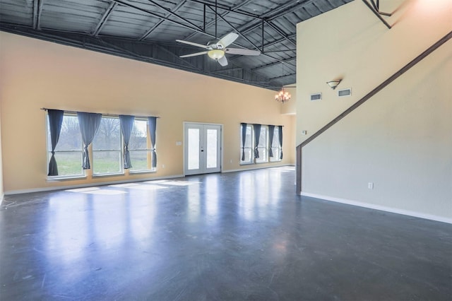 unfurnished living room featuring visible vents, baseboards, finished concrete flooring, and a towering ceiling