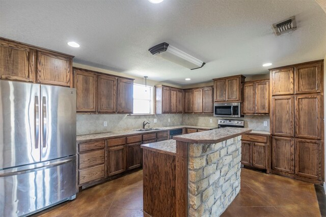 kitchen featuring visible vents, a sink, decorative backsplash, light countertops, and stainless steel appliances