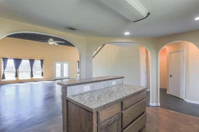 kitchen featuring visible vents, a kitchen island, concrete floors, and light countertops