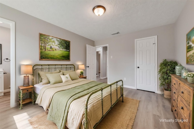 bedroom featuring visible vents, light wood-style flooring, and baseboards