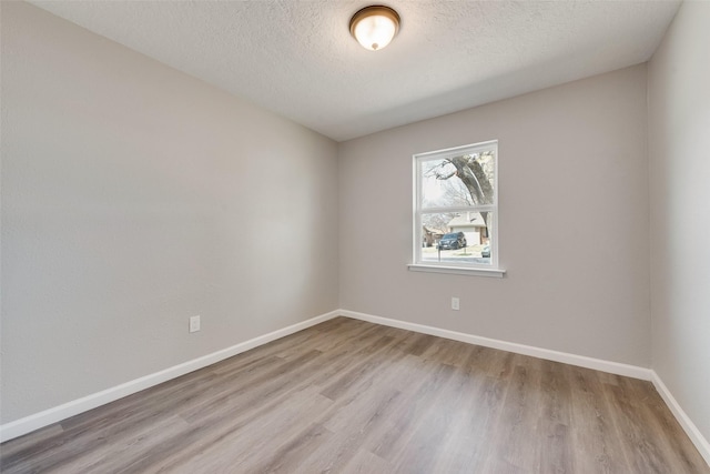 spare room featuring a textured ceiling, baseboards, and wood finished floors