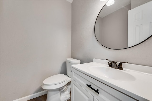 bathroom with toilet, vanity, and baseboards