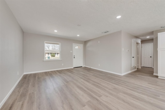 unfurnished room with light wood-style floors, baseboards, and a textured ceiling