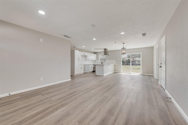 unfurnished living room with visible vents, a textured ceiling, baseboards, and light wood-style floors