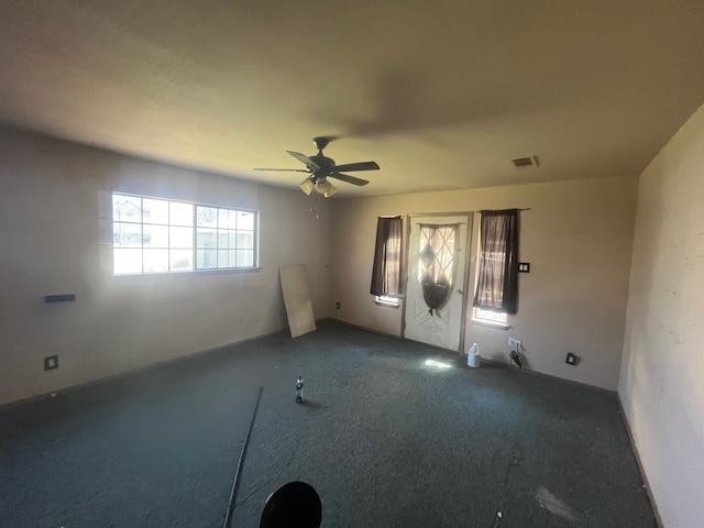 empty room featuring visible vents, carpet, and ceiling fan