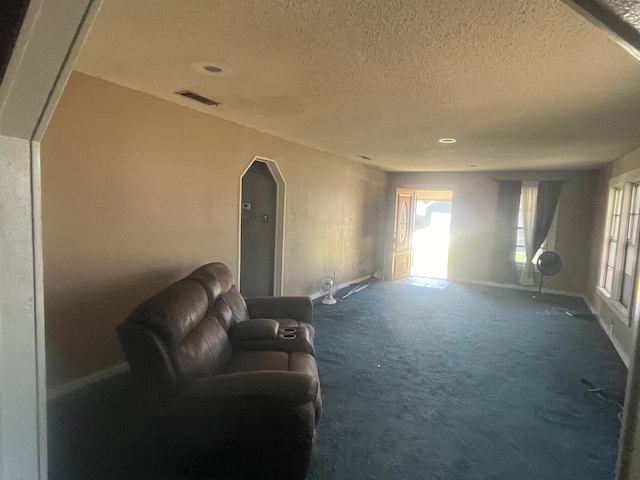 living room with baseboards, visible vents, arched walkways, a textured ceiling, and carpet flooring