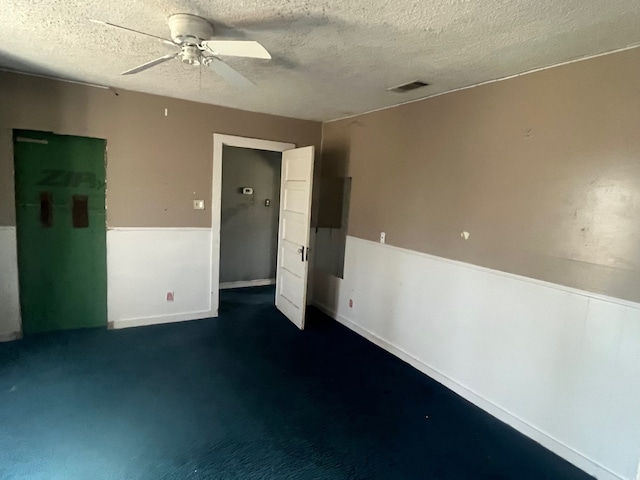 unfurnished room featuring visible vents, a textured ceiling, and a ceiling fan