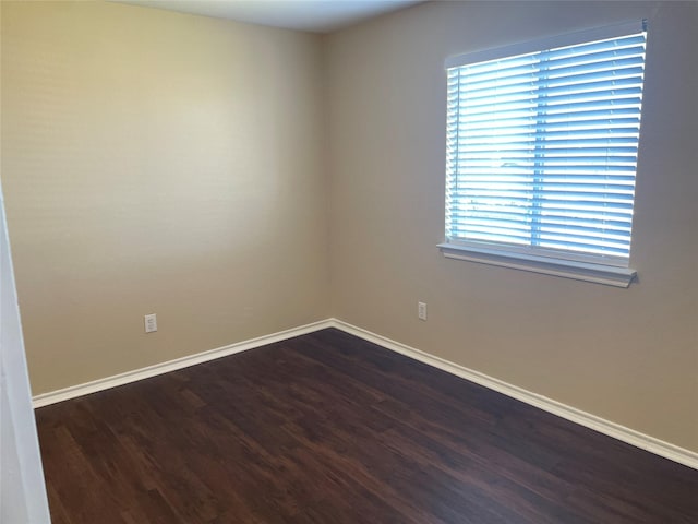 spare room featuring dark wood finished floors and baseboards