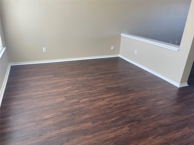 spare room featuring dark wood-style floors and baseboards