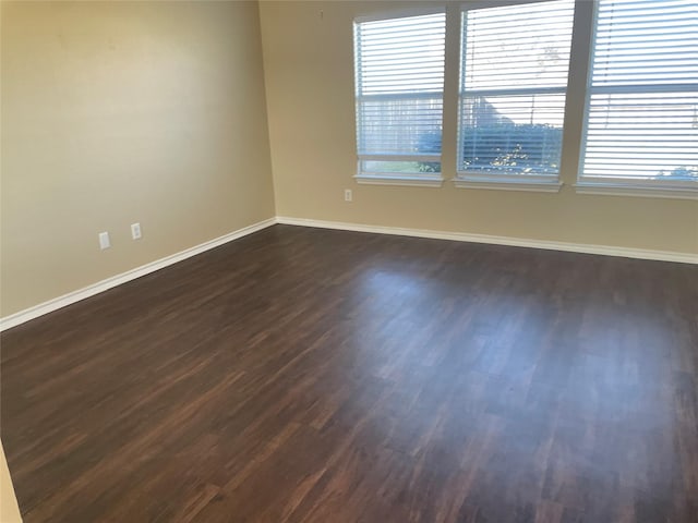 spare room featuring dark wood-type flooring and baseboards