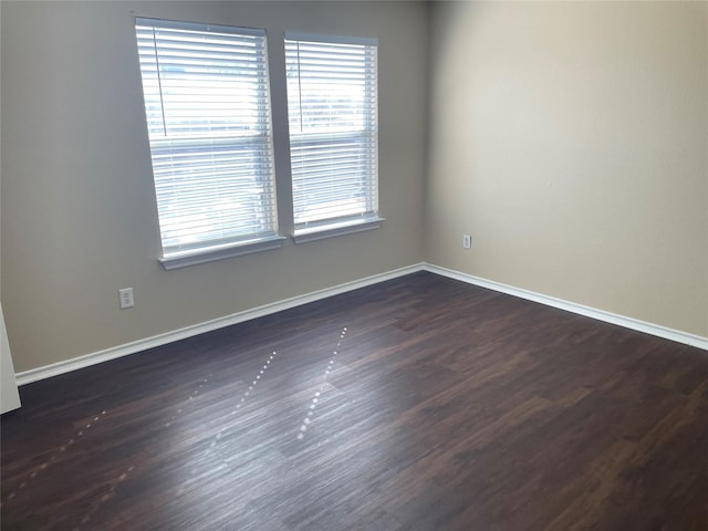 spare room with dark wood finished floors and baseboards