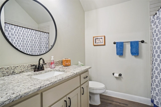 bathroom with vanity, wood finished floors, baseboards, vaulted ceiling, and toilet