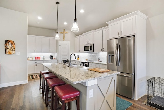 kitchen featuring tasteful backsplash, dark wood finished floors, stainless steel appliances, and a sink