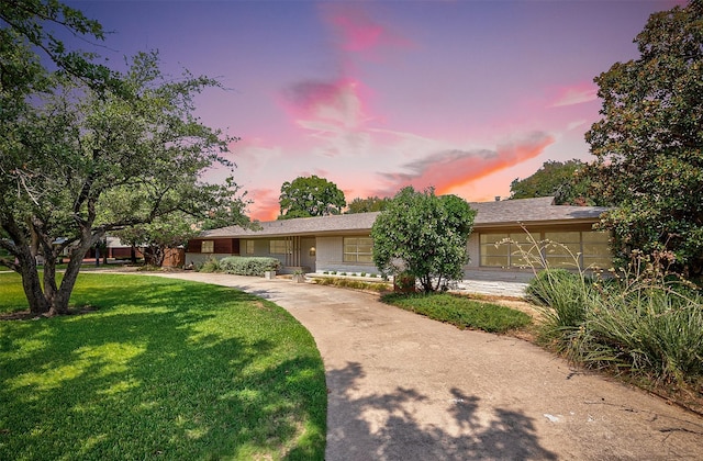 single story home featuring a lawn and concrete driveway