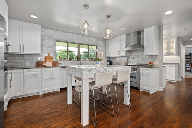 kitchen featuring dark wood-style flooring, appliances with stainless steel finishes, wall chimney exhaust hood, and white cabinets