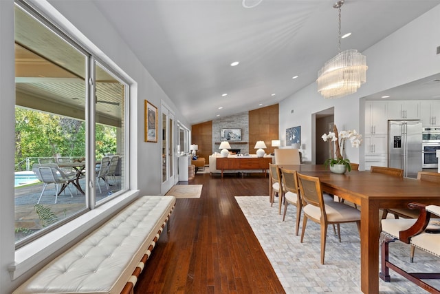 dining space featuring a large fireplace, lofted ceiling, recessed lighting, a notable chandelier, and dark wood-style flooring