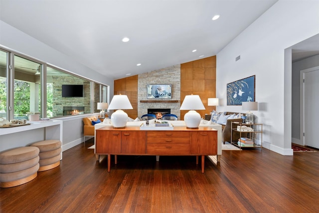 living area with a stone fireplace, lofted ceiling, and dark wood-style flooring