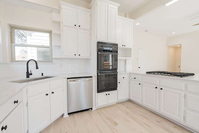 kitchen featuring open shelves, stainless steel appliances, backsplash, a sink, and light wood finished floors