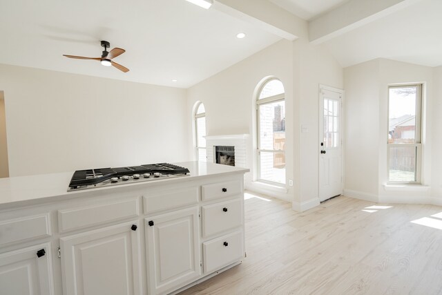 kitchen featuring stainless steel gas stovetop, vaulted ceiling with beams, a healthy amount of sunlight, and a brick fireplace