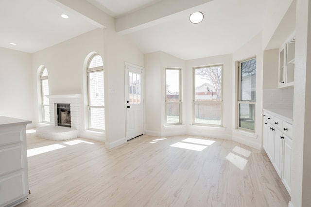 entryway featuring a brick fireplace, vaulted ceiling with beams, baseboards, light wood-type flooring, and recessed lighting