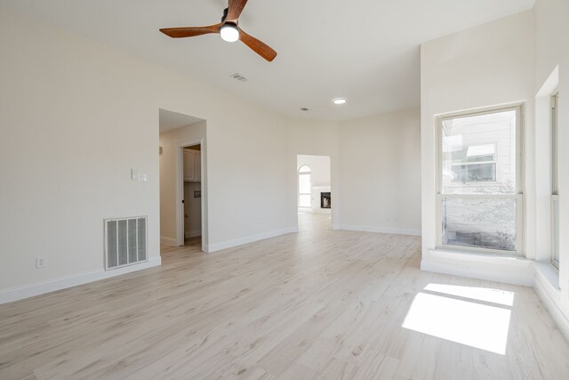 empty room with light wood finished floors, visible vents, a ceiling fan, and plenty of natural light