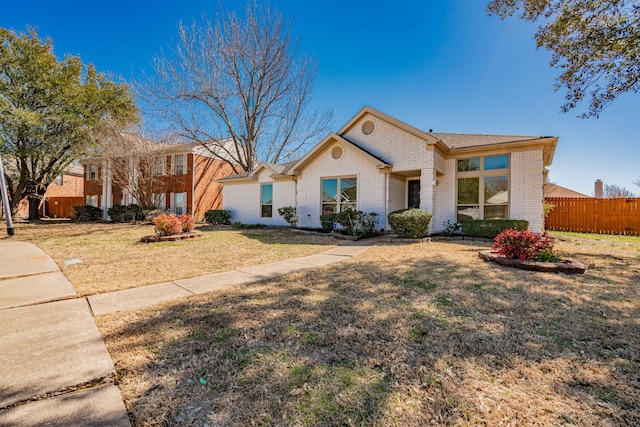 view of front of house with a front yard, fence, and brick siding