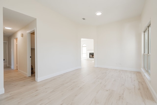 spare room with visible vents, baseboards, a fireplace, and light wood-type flooring
