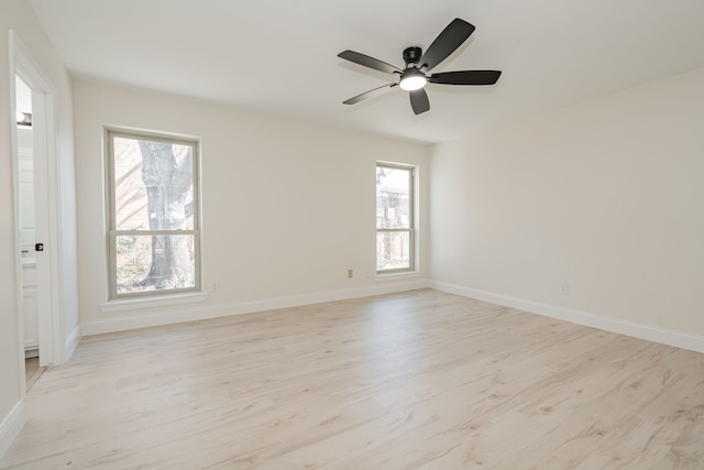 empty room with baseboards, a ceiling fan, and light wood finished floors