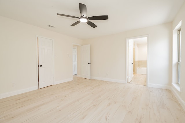 unfurnished bedroom featuring ensuite bath, baseboards, visible vents, and light wood finished floors