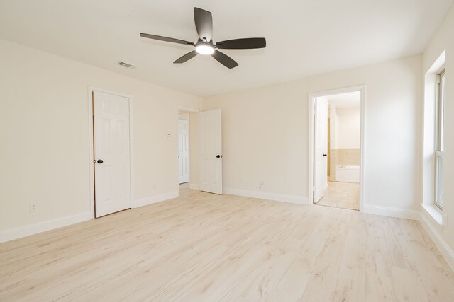 unfurnished bedroom featuring light wood finished floors, multiple windows, ensuite bath, baseboards, and visible vents