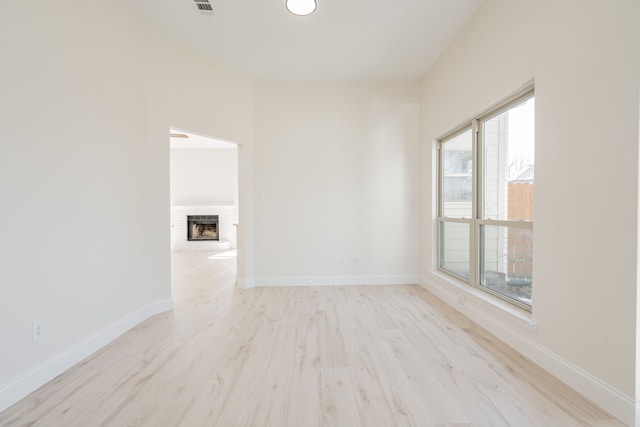 spare room featuring visible vents, a brick fireplace, wood finished floors, and baseboards