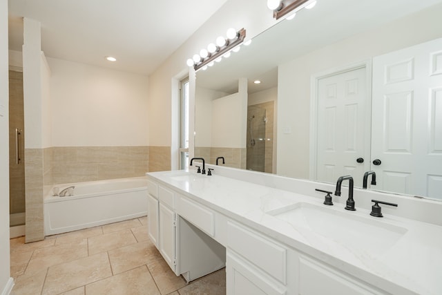 full bath with a shower stall, double vanity, a sink, and a garden tub