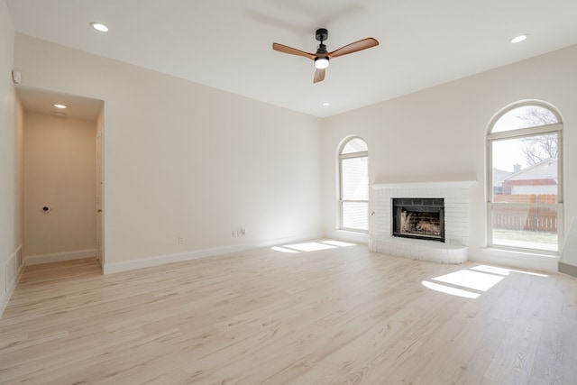 unfurnished living room featuring plenty of natural light, recessed lighting, a fireplace, and light wood-type flooring