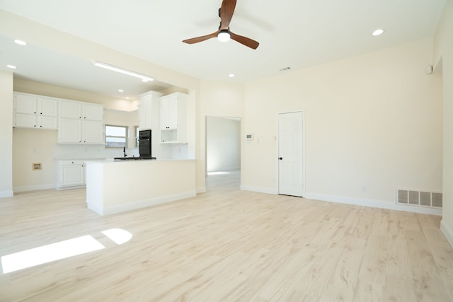 interior space featuring visible vents, light wood-type flooring, a peninsula, white cabinets, and open floor plan