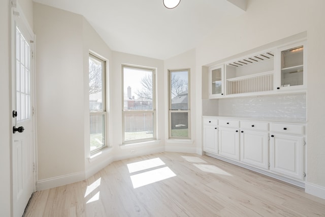 interior space with vaulted ceiling, light wood-style floors, and baseboards