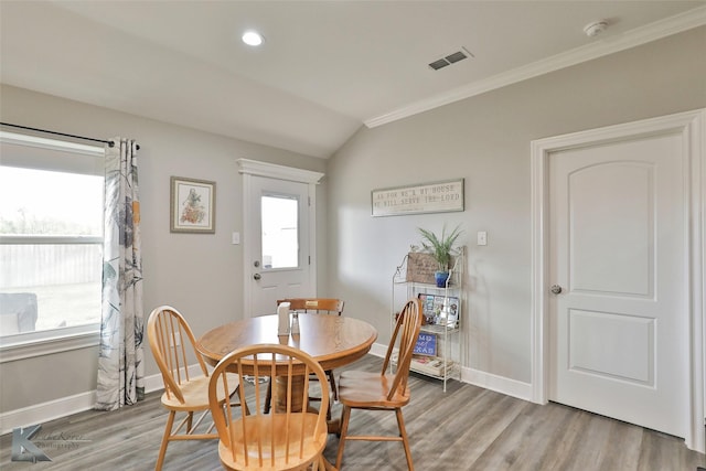 dining room featuring visible vents, baseboards, lofted ceiling, ornamental molding, and wood finished floors