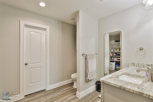 bathroom featuring toilet, vanity, baseboards, and wood finished floors