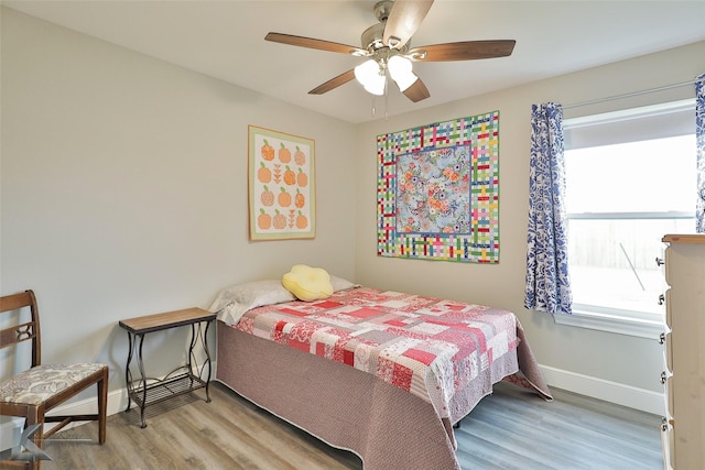 bedroom featuring ceiling fan, baseboards, and wood finished floors