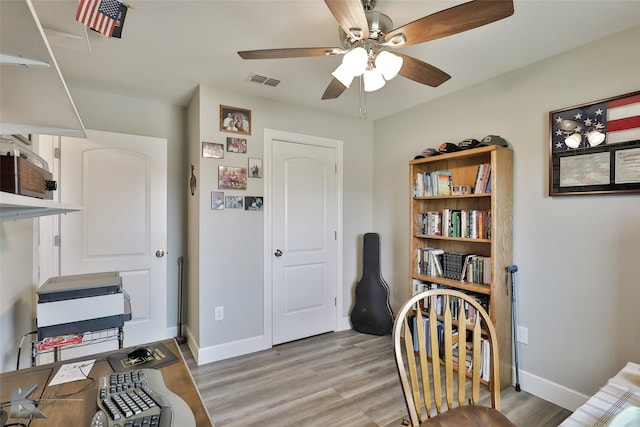 office space featuring a ceiling fan, light wood-style flooring, baseboards, and visible vents