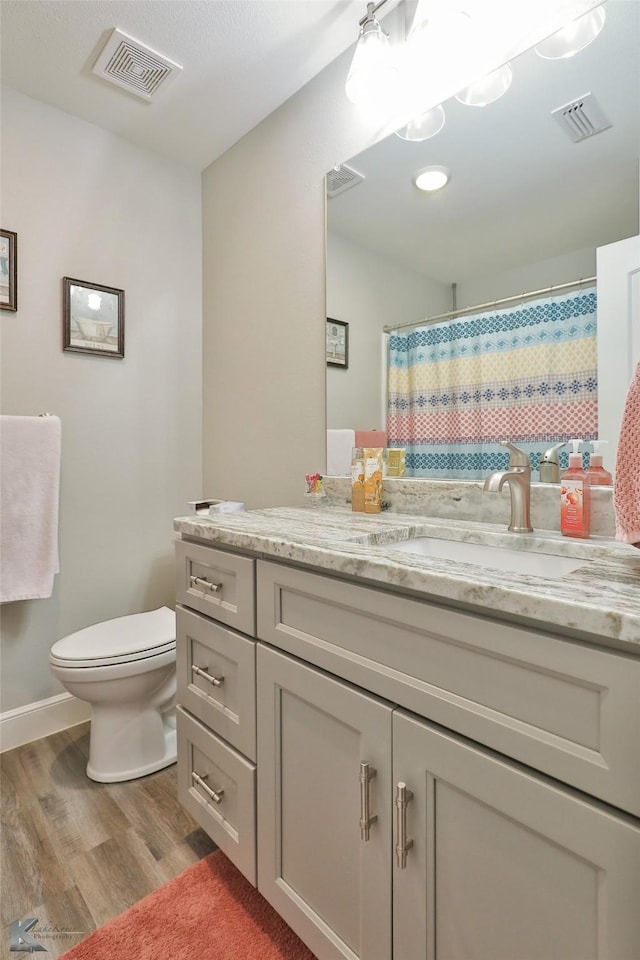 full bath with vanity, toilet, wood finished floors, and visible vents