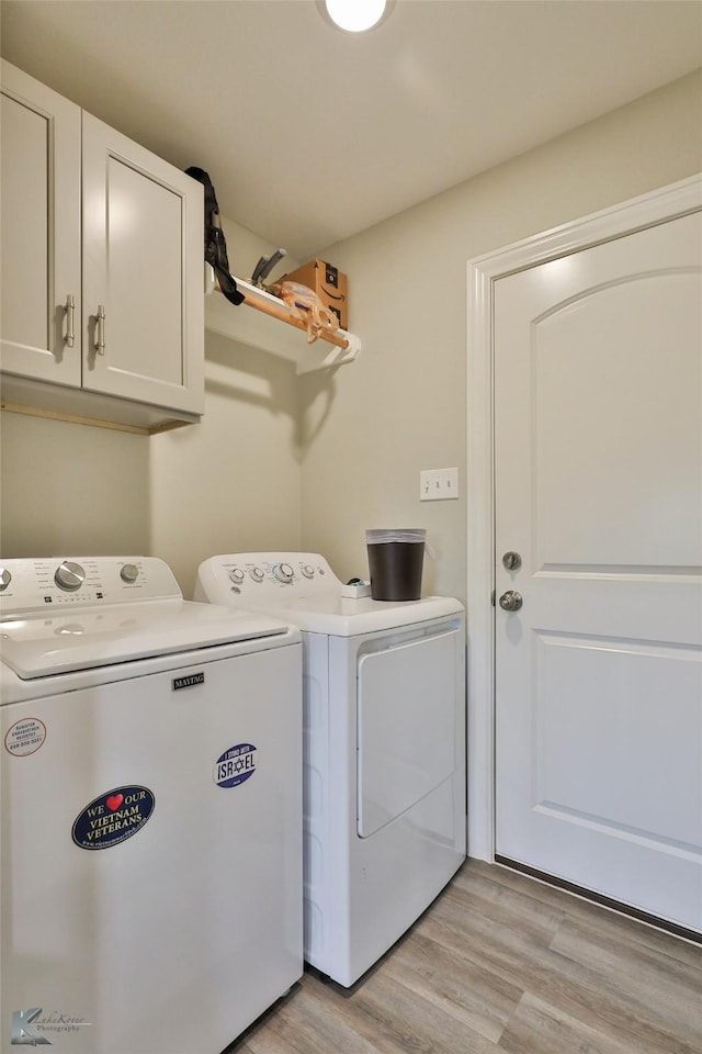 washroom featuring light wood-type flooring, cabinet space, and washer and clothes dryer