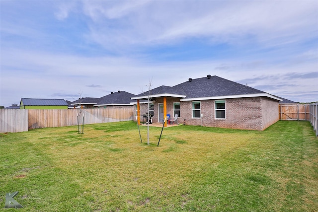 rear view of house with a lawn, brick siding, and a fenced backyard