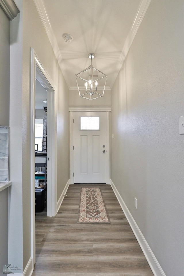 entryway featuring a chandelier, baseboards, wood finished floors, and crown molding