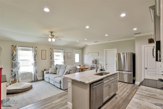 kitchen featuring a sink, light wood-style floors, appliances with stainless steel finishes, and an island with sink