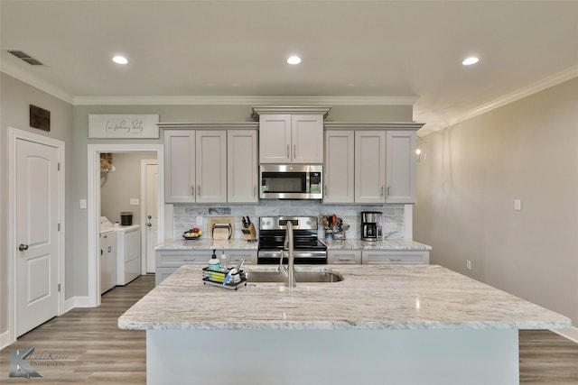 kitchen with visible vents, ornamental molding, washer and dryer, stainless steel appliances, and decorative backsplash