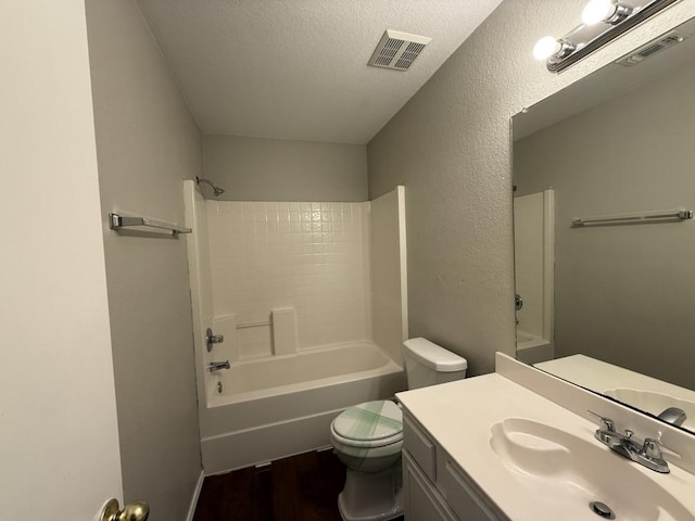 bathroom with visible vents, toilet, vanity, and a textured ceiling