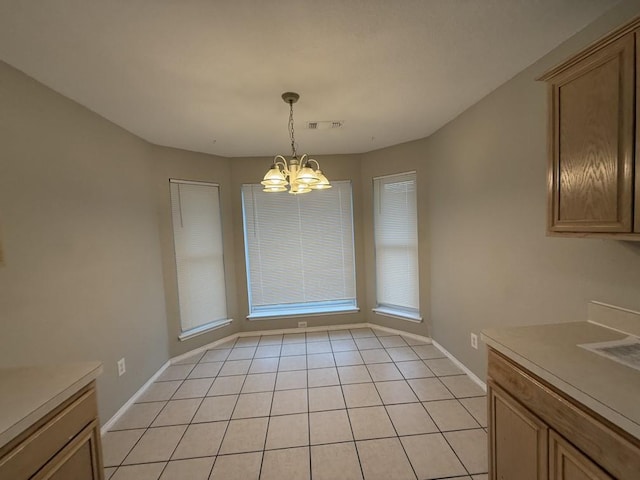 unfurnished dining area with light tile patterned floors, visible vents, baseboards, and a chandelier