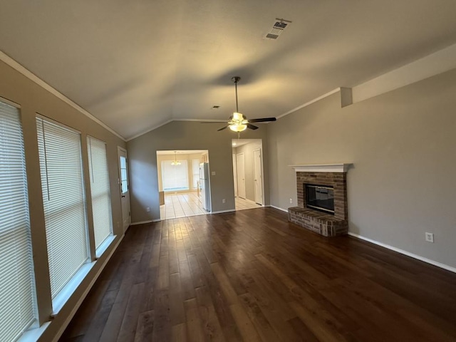 unfurnished living room featuring visible vents, wood finished floors, a fireplace, crown molding, and vaulted ceiling