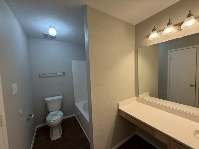 full bathroom with visible vents, toilet, baseboards, vanity, and a textured wall