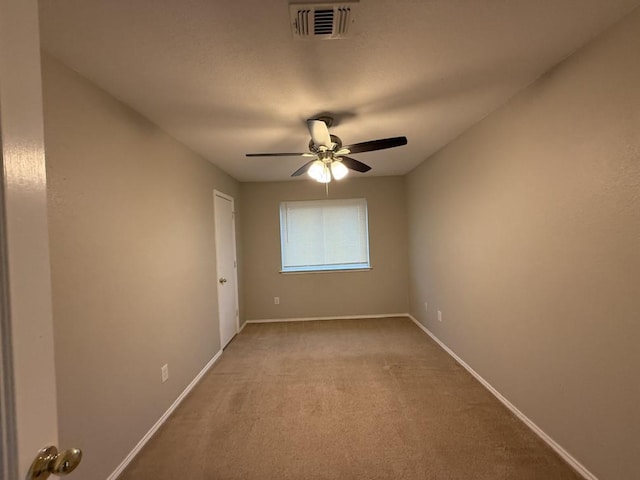 carpeted empty room featuring visible vents, baseboards, and ceiling fan